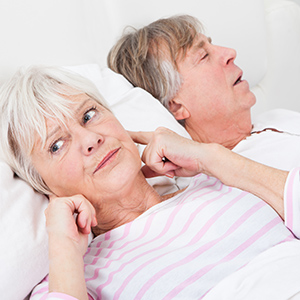 man snoring with wife plugging her ears